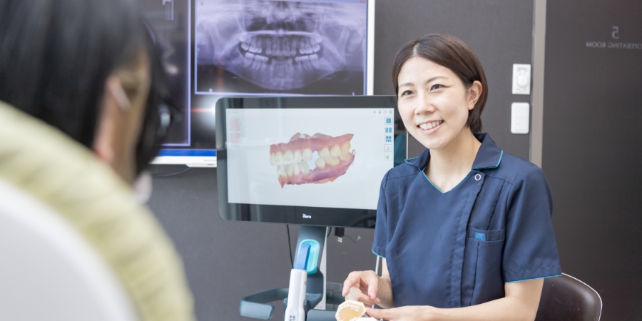 診察の様子 歯の模型を使いながら治療計画の説明を患者にしている